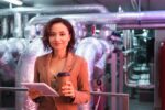 young engineer with digital tablet and coffee to go smiling at camera in technical room of data